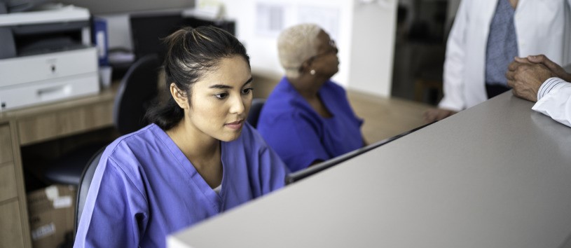 Health Information Specialist working at a computer behind a desk.